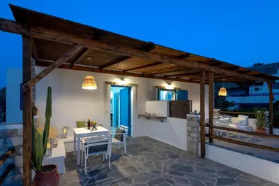 a patio with a white table and a kitchen at Agnanti Beach Apartments in Archangelos