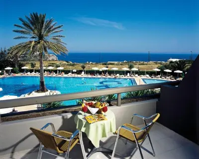 a balcony with a table and chairs and a pool at Cathrin Hotel in Faliraki