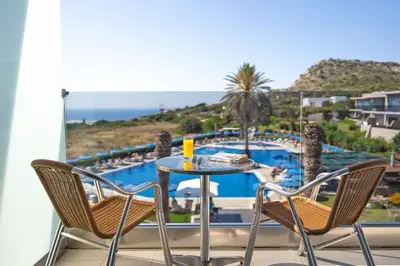 a table and chairs on a balcony with a view of a pool at Cathrin Hotel in Faliraki