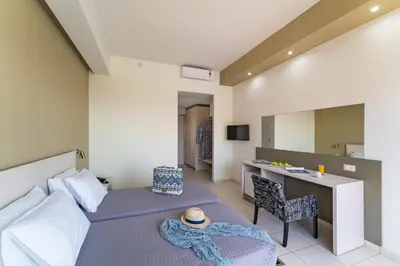 a bedroom with a bed and a desk with a hat on it at Cathrin Hotel in Faliraki