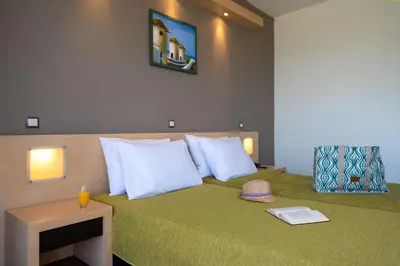 a hotel room with a bed with a green bedspread at Cathrin Hotel in Faliraki