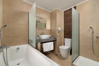 a bathroom with a tub and a toilet and a sink at Virginia Family Resort in Kallithea Rhodes