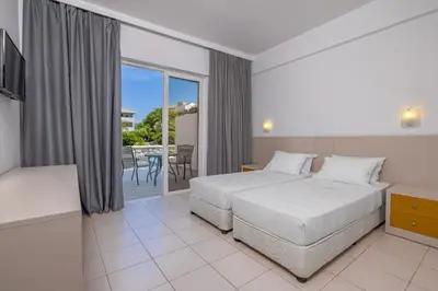 a hotel room with two beds and a balcony at Virginia Family Resort in Kallithea Rhodes