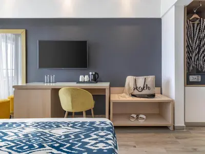 a bedroom with a bed and a desk with a television at Mercure Rhodes Alexia Hotel & Spa in Rhodes Town