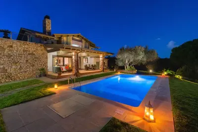 a villa with a swimming pool at night at Blue & Green View Villa in Asgourou