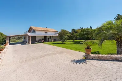 a house with a driveway and a palm tree at Blue & Green View Villa in Asgourou