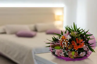 a bouquet of flowers on a table in a bedroom at Terinikos Sunny Garden Hotel & Junior Suites in Ialyssos