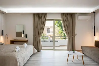 a bedroom with a bed and a couch and a window at Terinikos Sunny Garden Hotel & Junior Suites in Ialyssos