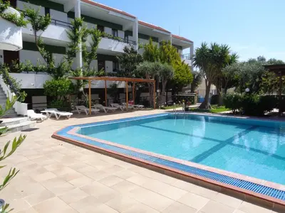a swimming pool in front of a building at Terinikos Sunny Garden Hotel & Junior Suites in Ialyssos