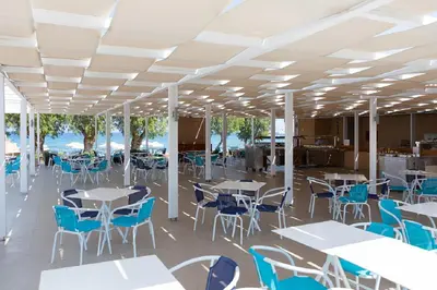 a cafeteria with tables and chairs and the ocean at Doreta Beach in Theologos