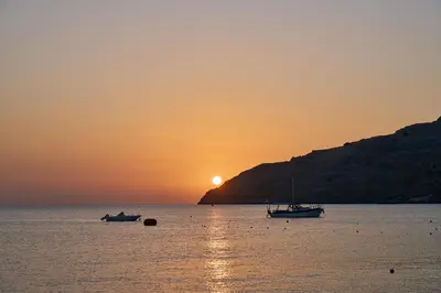 two boats sitting in the water at sunset at Lindos Royal Resort in Líndos