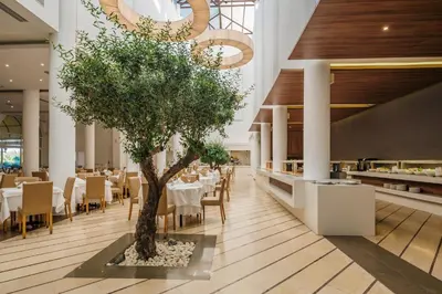 a restaurant with a tree in the middle of the floor at Lindos Royal Resort in Líndos