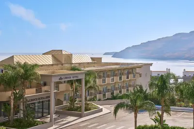 a building with palm trees in front of the ocean at Lindos Royal Resort in Líndos