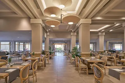 a dining room with tables and chairs and windows at Lindos Imperial Resort & Spa in Kiotari