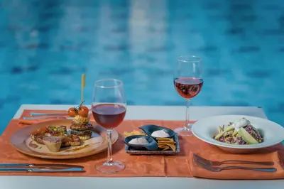 a table with two glasses of wine and a plate of food at Lindos Imperial Resort & Spa in Kiotari