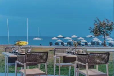 a table and chairs with tables and umbrellas on the beach at Lindos Imperial Resort & Spa in Kiotari