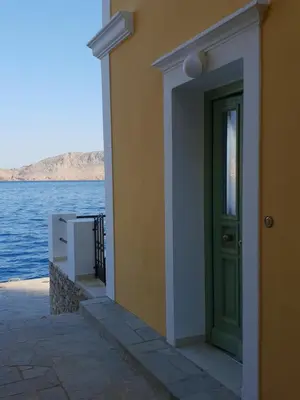 a building with a green door next to the water at Sea Stars ,Villas Danezis in Symi