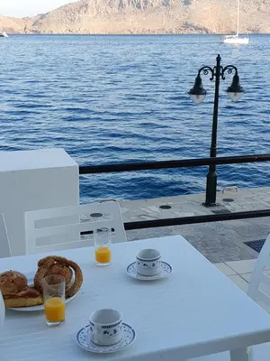 a table with a plate of food and orange juice at Sea Stars ,Villas Danezis in Symi