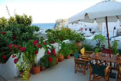 a patio with tables and chairs and potted plants at Erato Apartments in Líndos