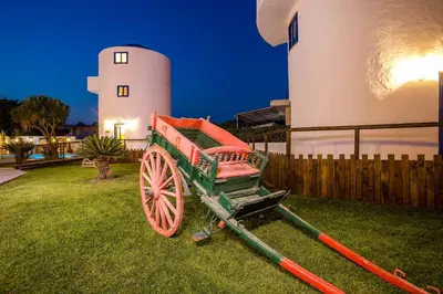 a cart sitting in the grass in front of a lighthouse at Christina Dream Village in Pastida