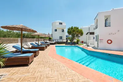 a pool with chairs and umbrellas next to a building at Christina Dream Village in Pastida