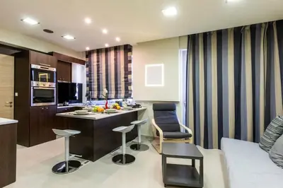 a kitchen and living room with a counter and chairs at Rhodes Central Suite in Rhodes Town