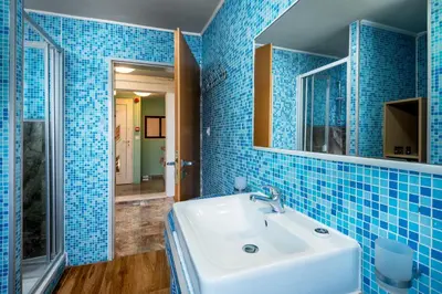 a blue tiled bathroom with a sink and a mirror at Comfort Hotel Apartments in Rhodes Town