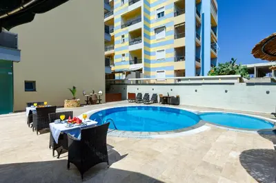 a pool with tables and chairs next to a building at Comfort Hotel Apartments in Rhodes Town