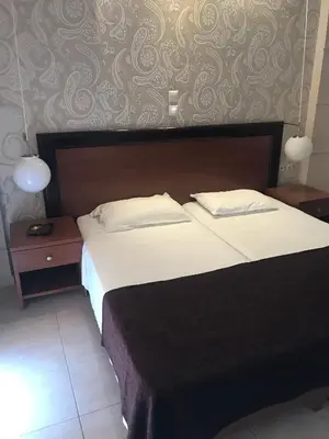 a bedroom with a large bed and two night stands at Saint Amon Hotel in Faliraki