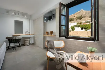 a living room with a window and a table and chairs at Lindos Amphitheater Villas and Apartments in Líndos