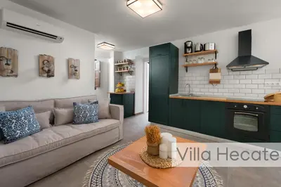 a living room with a couch and a kitchen at Lindos Amphitheater Villas and Apartments in Líndos