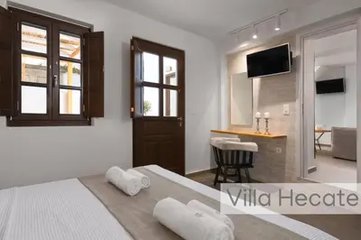 a bedroom with two beds and a kitchen in the background at Lindos Amphitheater Villas and Apartments in Líndos