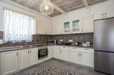 a kitchen with white cabinets and a stainless steel refrigerator at White Passion in Afantou