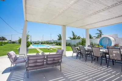 a patio with a table and chairs and a pool at White Passion in Afantou