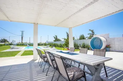 a patio with a table and chairs and a pool at White Passion in Afantou