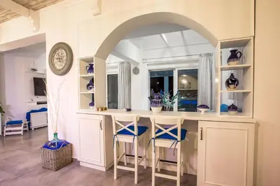 a kitchen with a counter with chairs and a clock at White Passion in Afantou