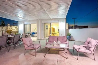 a patio with pink chairs and a table and a kitchen at White Passion in Afantou