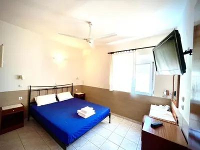 a bedroom with a blue bed and a flat screen tv at SCALA APARTS & STUDIOS - Rhodes in Afantou