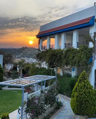 a building with the sun setting in the background at SCALA APARTS & STUDIOS - Rhodes in Afantou