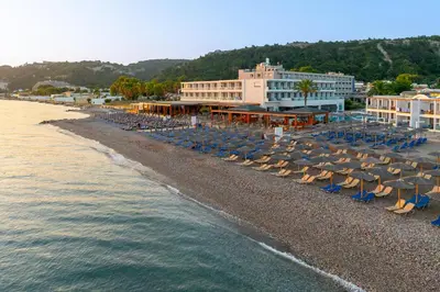 a beach with chairs and umbrellas next to the water at Avra Beach Resort in Ixia