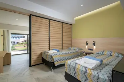 a hotel room with two beds and a television at Avra Beach Resort in Ixia