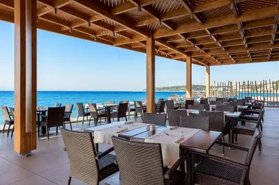 a restaurant on the beach with tables and chairs at Avra Beach Resort in Ixia