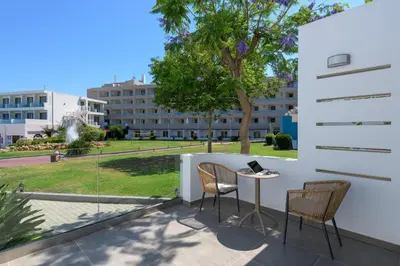 a balcony with a table and chairs and a building at Avra Beach Resort in Ixia