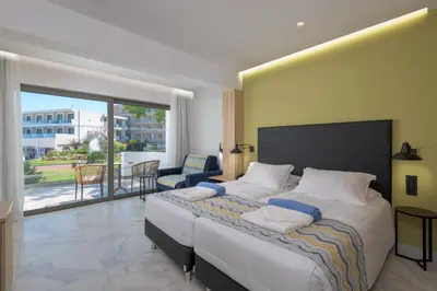 a bedroom with a large bed and a balcony at Avra Beach Resort in Ixia