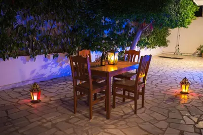 a wooden table with chairs and lights on a patio at Blue Roses in Ixia