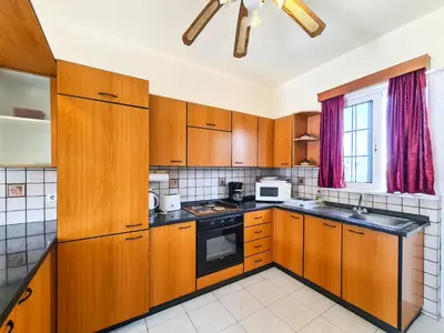 a kitchen with wooden cabinets and a stove top oven at Colonial Studio/Apartment in Faliraki