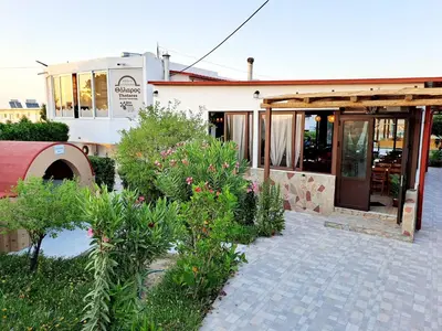 a building with a restaurant with plants in front of it at Evi Apartments And Studios in Theologos