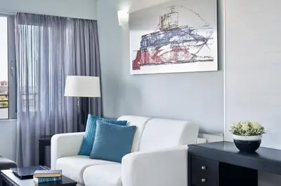 a living room with a white chair and a table at AQUAMARE CITY and BEACH in Rhodes Town