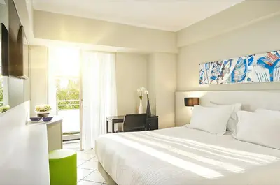 a bedroom with a bed and a desk and a window at AQUAMARE CITY and BEACH in Rhodes Town