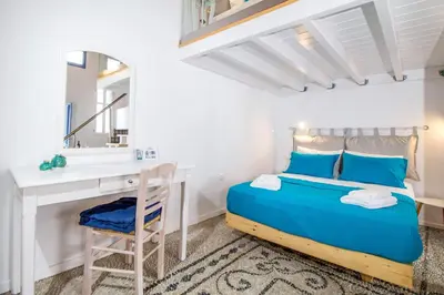 a bedroom with a bed and a desk and a mirror at The red door in Koskinou in Koskinou
